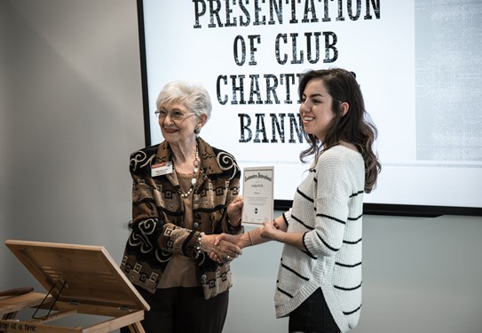 Distinguished Toastmaster Hallie Adams presents Courtney Vasquez with the LAVIDGE Ad Libs Charter certificate.