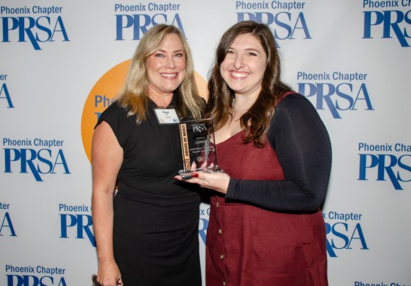 Megan Wahl, left; and Emma Wolff, right, on behalf of LAVIDGE Public Relations accept an Award of Merit from the Public Relations Society of America, Phoenix Chapter.