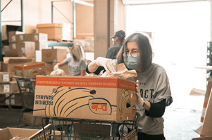 Laurie Schnebly adds great to a food box at Phoenix Rescue Mission's Hope for Hunger food bank.