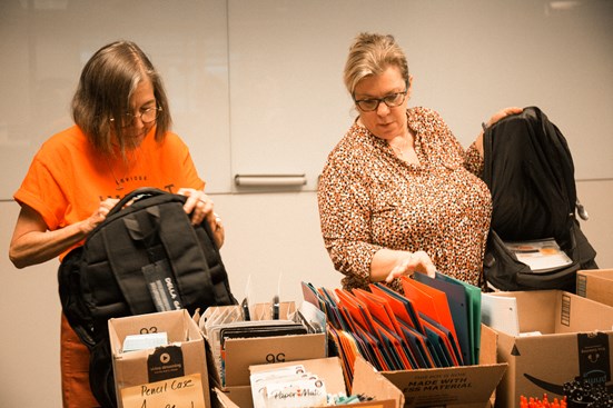 Laurie Schnebly and Ellen Frezzi of LAVIDGE IMPACT fill back packs with supplies for Save the Family Foundation's 2022 back-to-school drive.